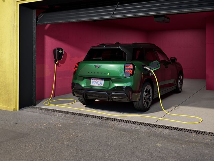 Prikaz stražnjeg kraja potpuno električnog MINI Aceman modela u British Racing Green boji koji se puni u garaži.