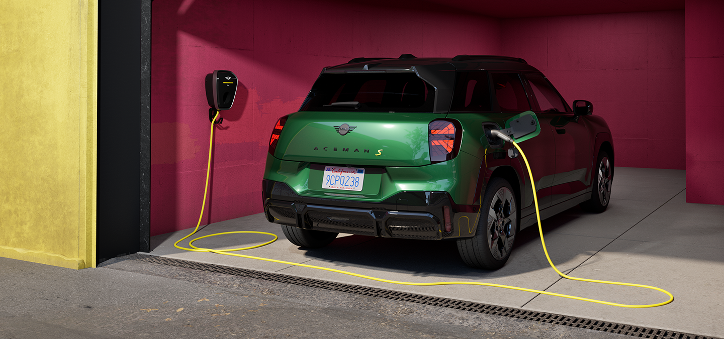 Prikaz stražnjeg kraja potpuno električnog MINI Aceman modela u British Racing Green boji koji se puni u garaži.