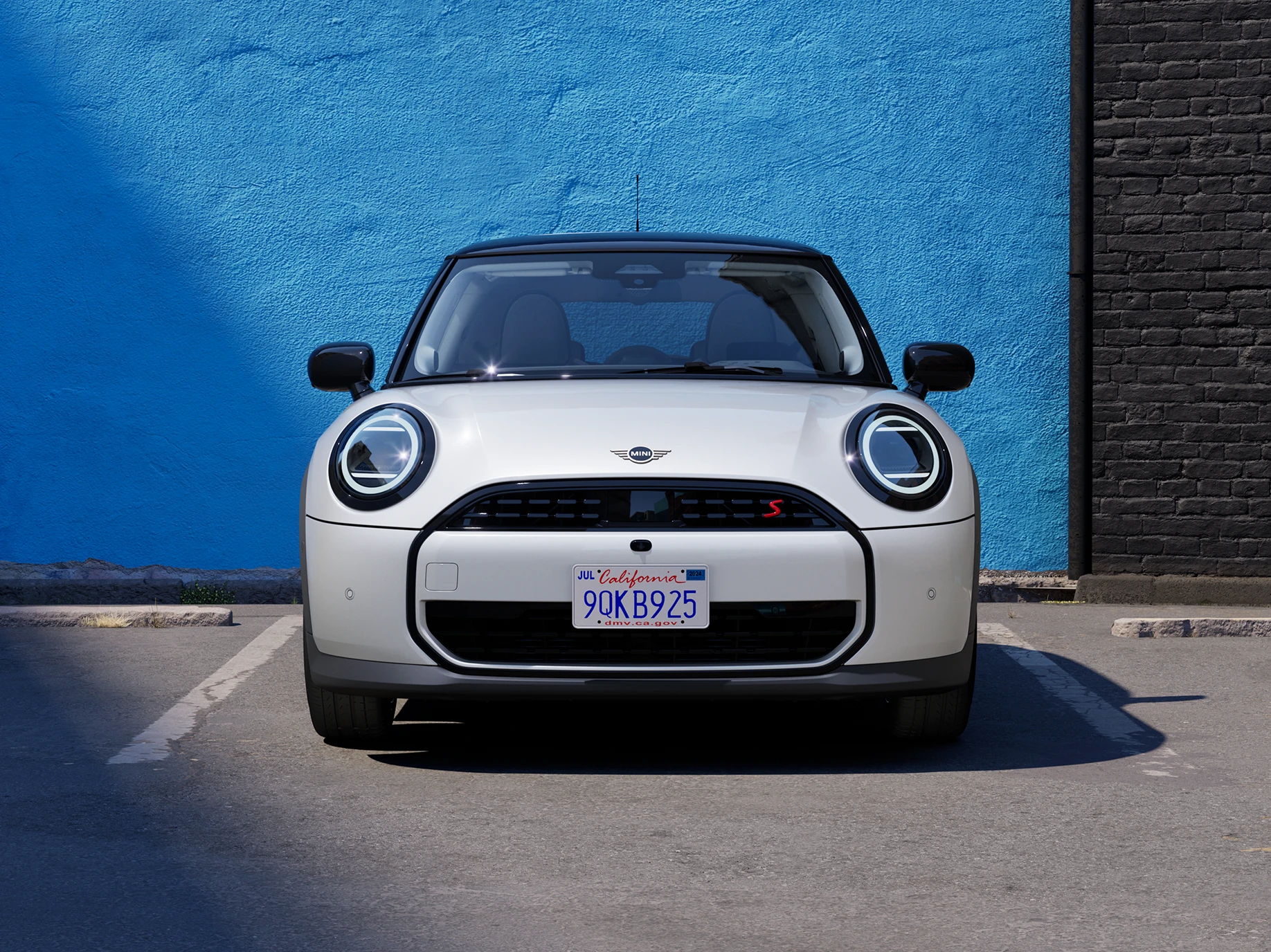 Prikaz prednjeg kraja parkiranog MINI Cooper modela u Nanuq White boji s krovom Black boje.