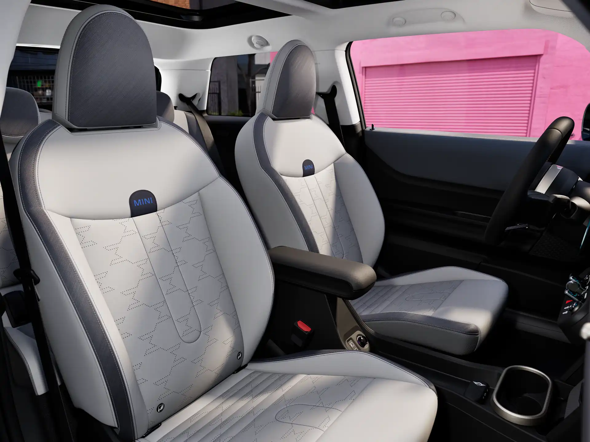 Unutarnja perspektiva MINI Coopera modela prikazuje nadzornu ploču, volan, okrugli zaslon, panoramski stakleni krov i naslon prednjih sjedala.