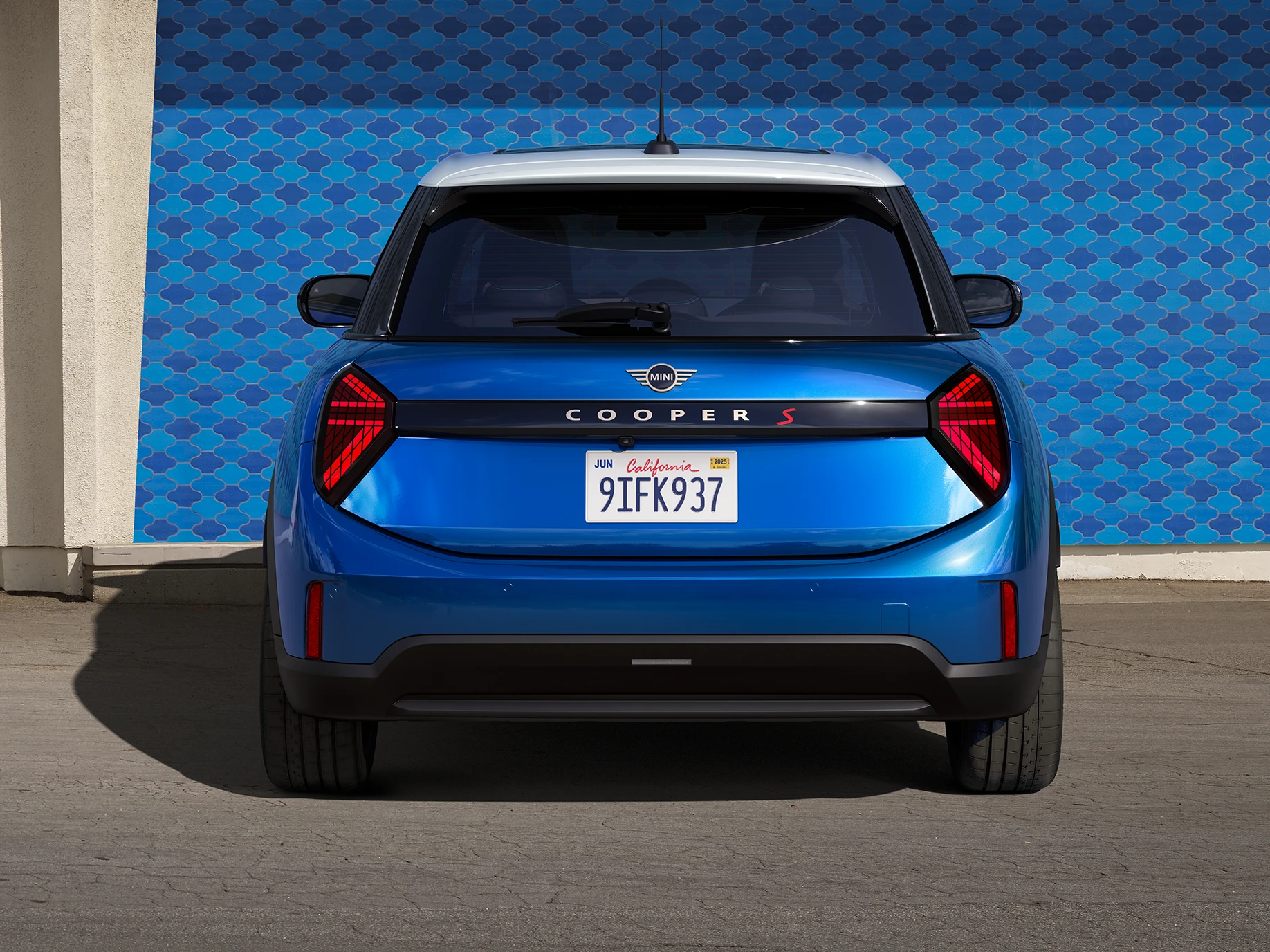 Prikaz stražnjeg kraja MINI Cooper modela s 5-vrata u Icy Sunshine Blue boji i krova u Multitone Roof Blue boji.
