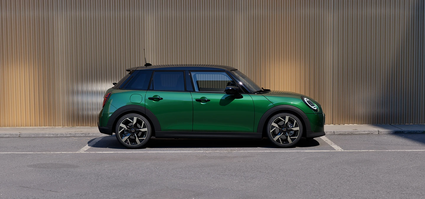 Bočni prikaz MINI Cooper modela s 5-vrata u British Racing Green boji i krova u Black boji na parkingu.