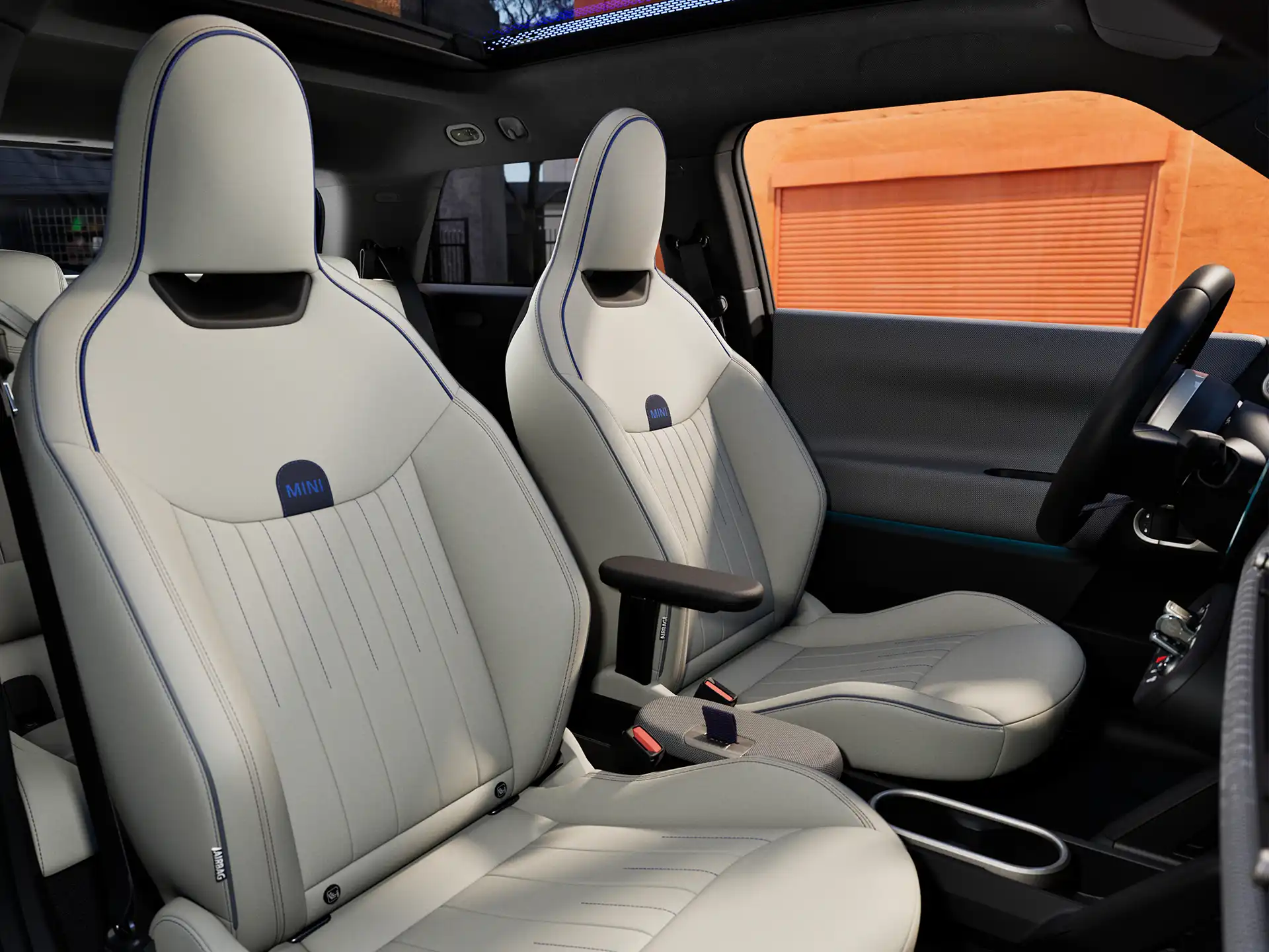 Perspektiva unutrašnjosti potpuno električnog MINI Cooper modela prikazuje nadzornu ploču, volan, okrugli zaslon, panoramski stakleni krov i naslon prednjih sjedala