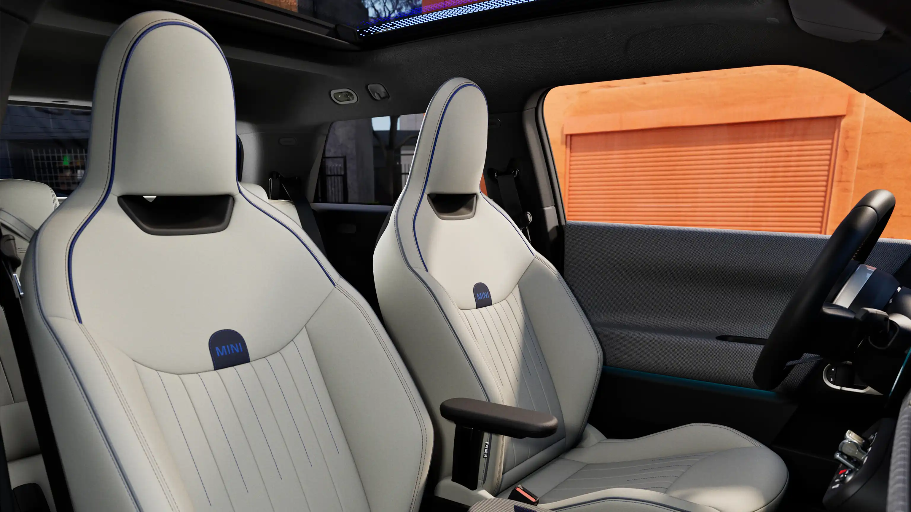 Perspektiva unutrašnjosti potpuno električnog MINI Cooper modela prikazuje nadzornu ploču, volan, okrugli zaslon, panoramski stakleni krov i naslon prednjih sjedala