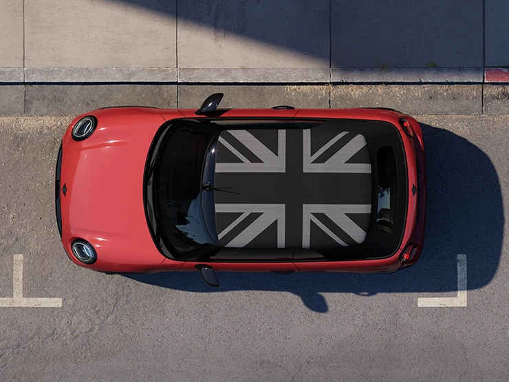 Prikaz MINI Cooper Cabrio modela iz zraka u Chili Red boji i krov MINI Yours dok stoji na cesti.