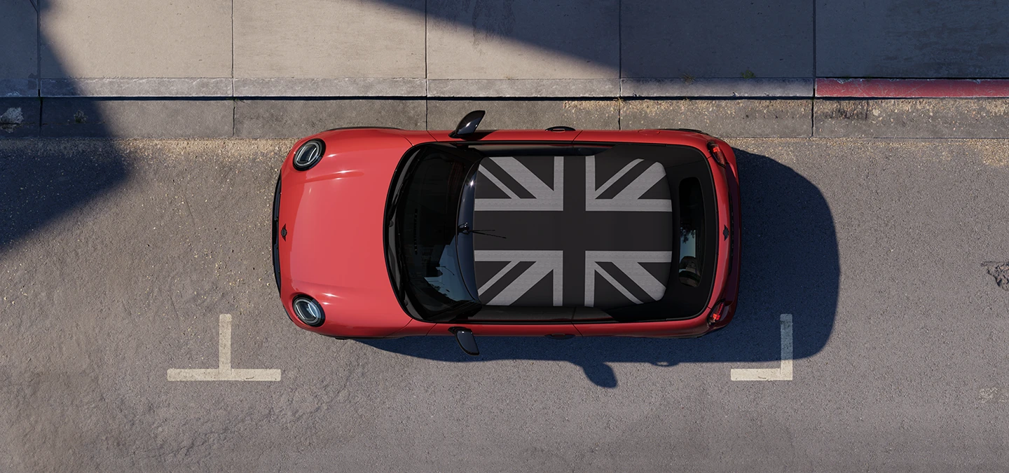 Prikaz MINI Cooper Cabrio modela iz zraka u Chili Red boji i krov MINI Yours dok stoji na cesti.