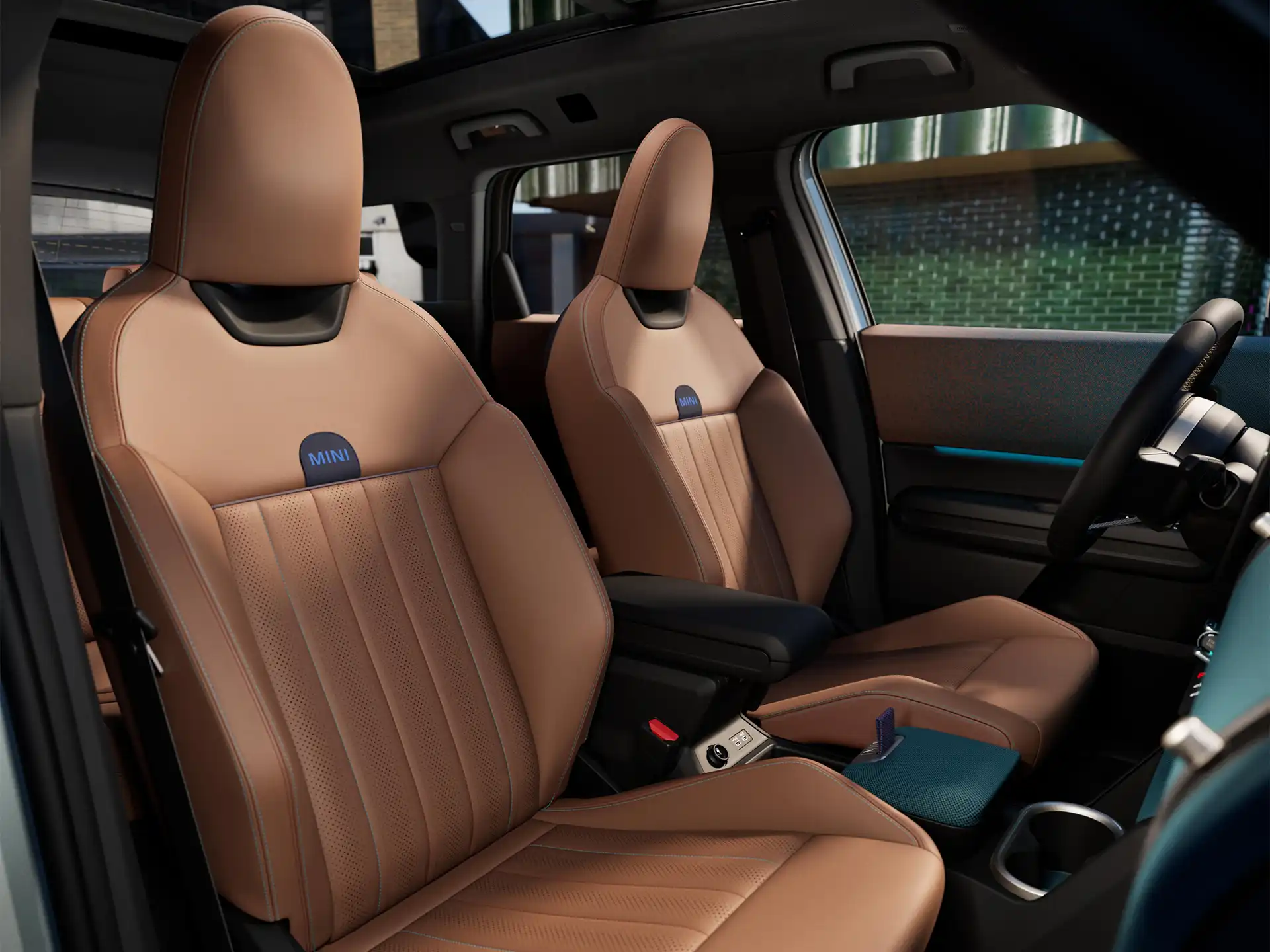 Unutarnja perspektiva potpuno električnog MINI Countryman modela prikazuje nadzornu ploču, upravljač, okrugli zaslon, panoramski stakleni krov i naslon prednjih sjedala.