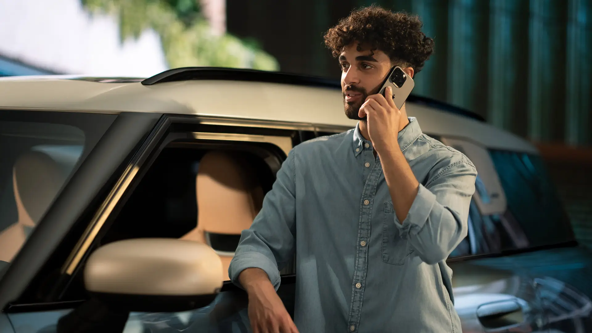 MINI Proactive Care — čovjek stoji pored svog MINI-a i razgovara telefonom sa savjetnikom servisnog centra.