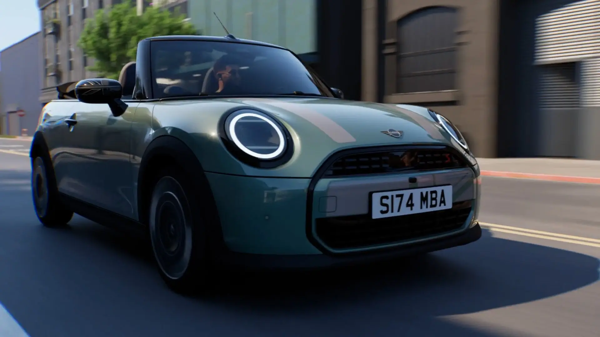 MINI Cabrio u Ocean Wave Green boji s MINI Heritage bijelim naljepnicama i Union Jack kućištima retrovizora tijekom vožnje gradom.