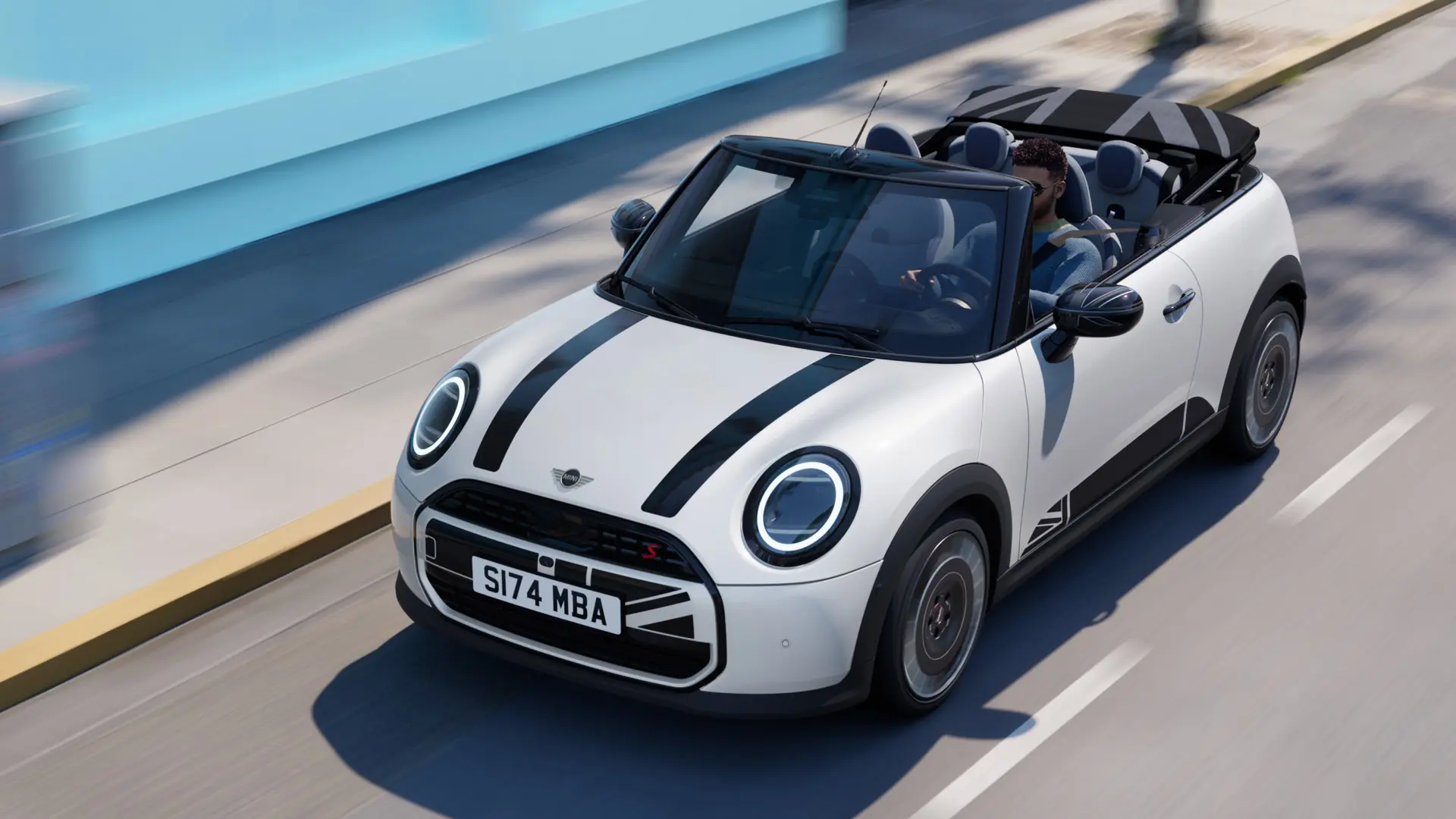 Prikaz MINI Cabrio modela iz zraka u Nanuq White boji s MINI Heritage naljepnicama na poklopcu u crnoj boji. 