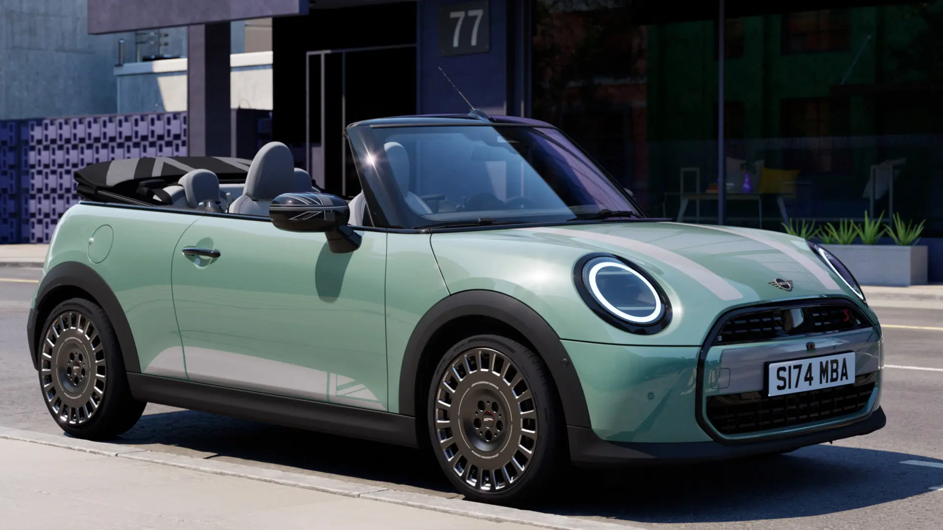 Prikaz prednjeg kraja MINI Cabrio modela u Ocean Wave Green boji s MINI Heritage naljepnicama na poklopcu u bijeloj boji. 