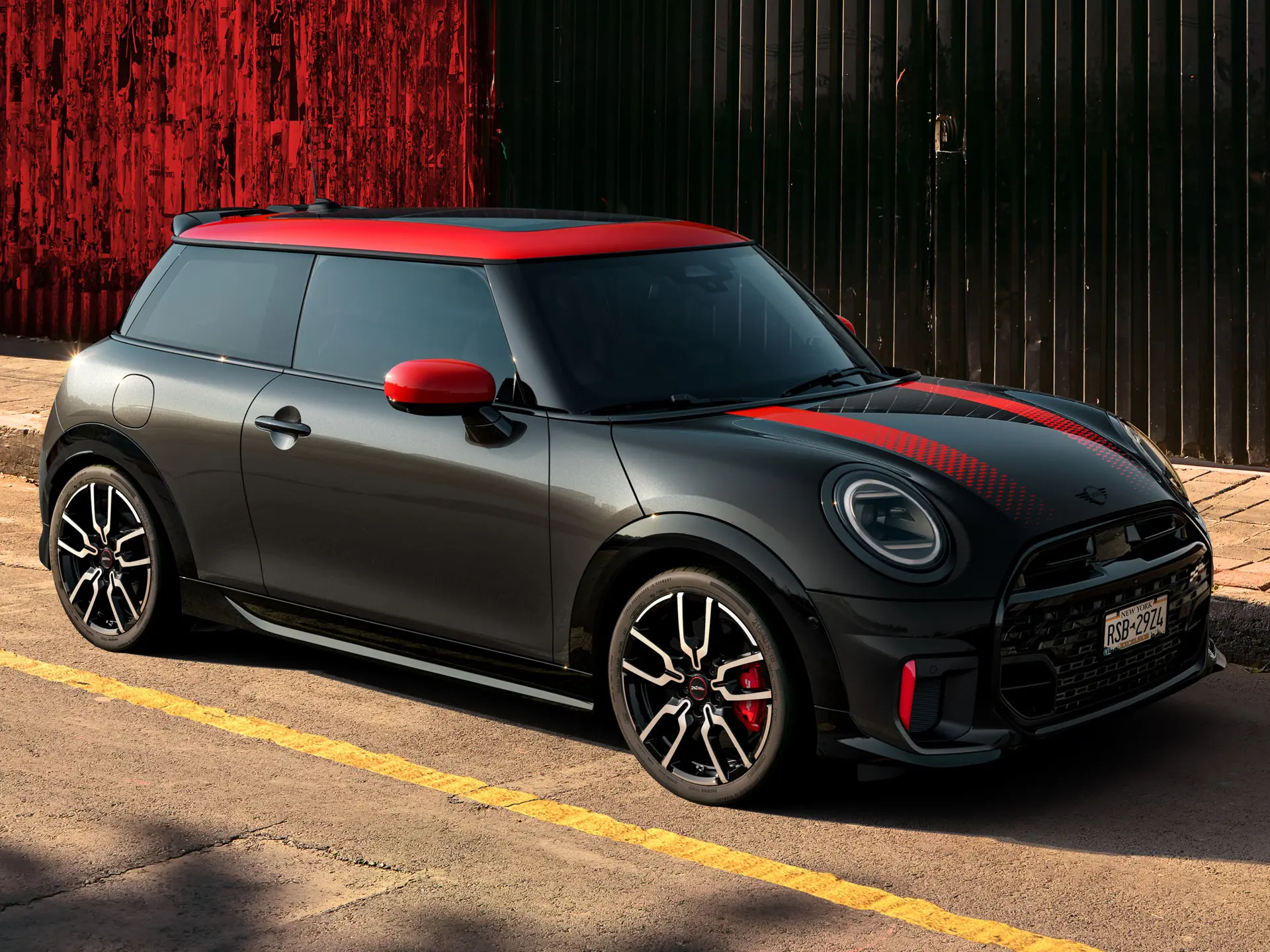 MINI John Cooper Works 3-door u Midnight Black boji s krovom i poklopcima retrovizora u Chilli Red boji i crvenim sportskim prugama, bočni pogled, parkiran na ulici. 