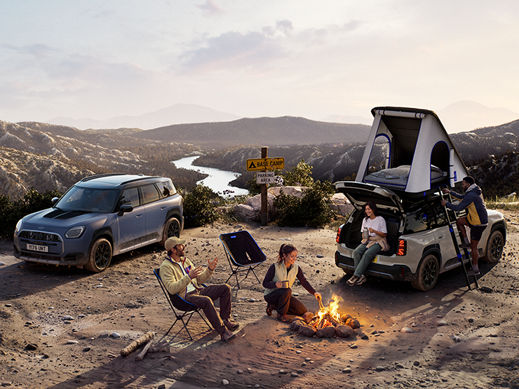 Prikaz dva MINI Countryman Untamed Edition vozila na planini u zalasku sunca.